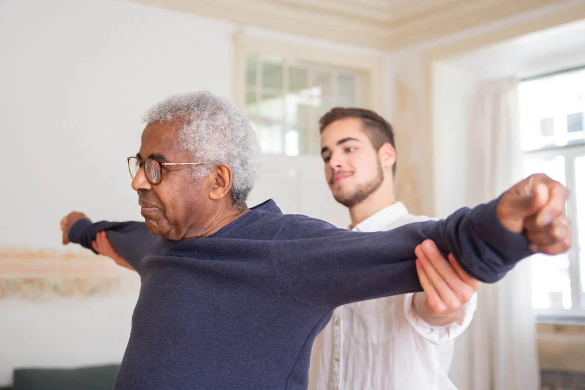 An older man doing a guided arm exercise with a practitioner.