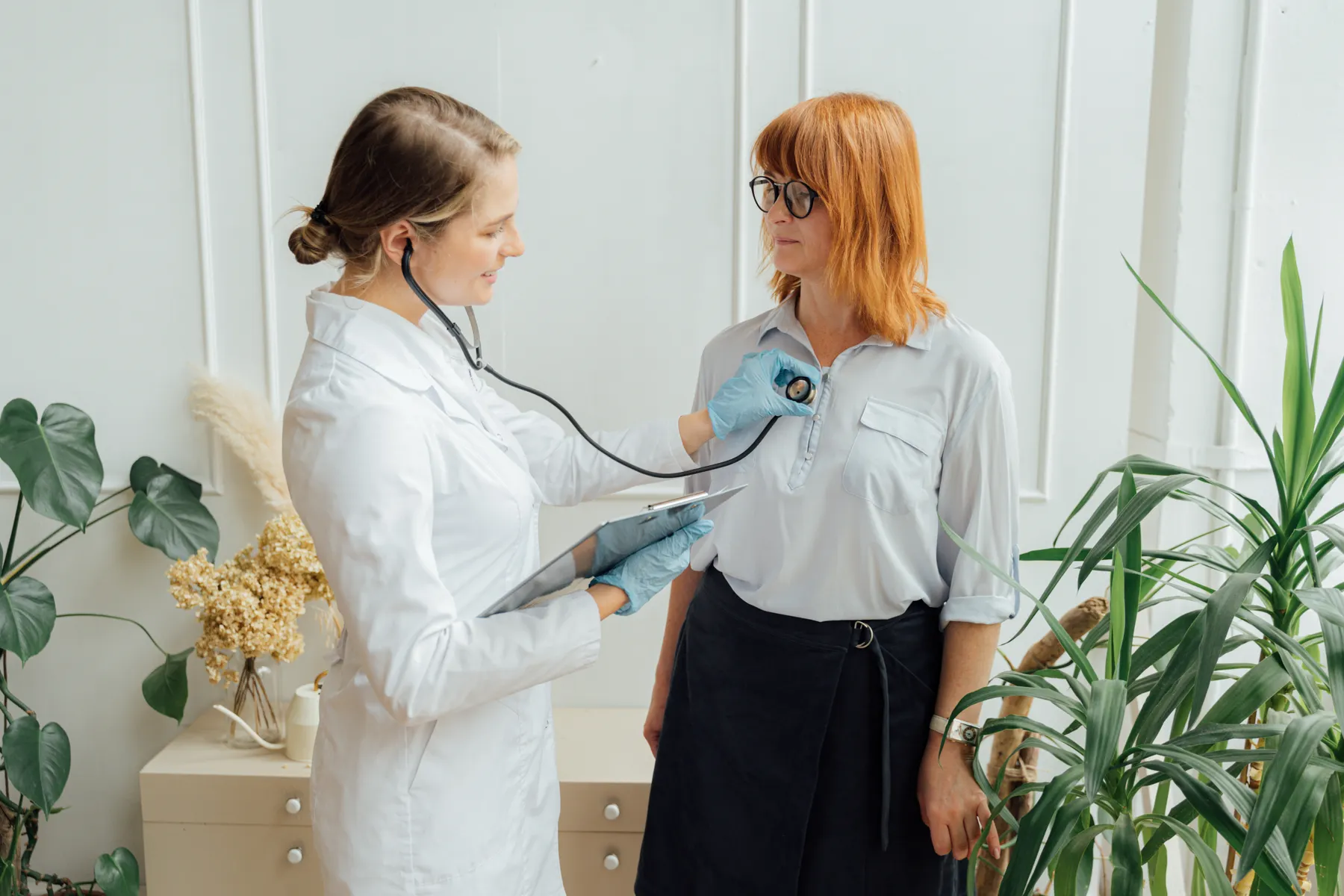 A clinician taking a blood-pressure reading in a bright consulting room.