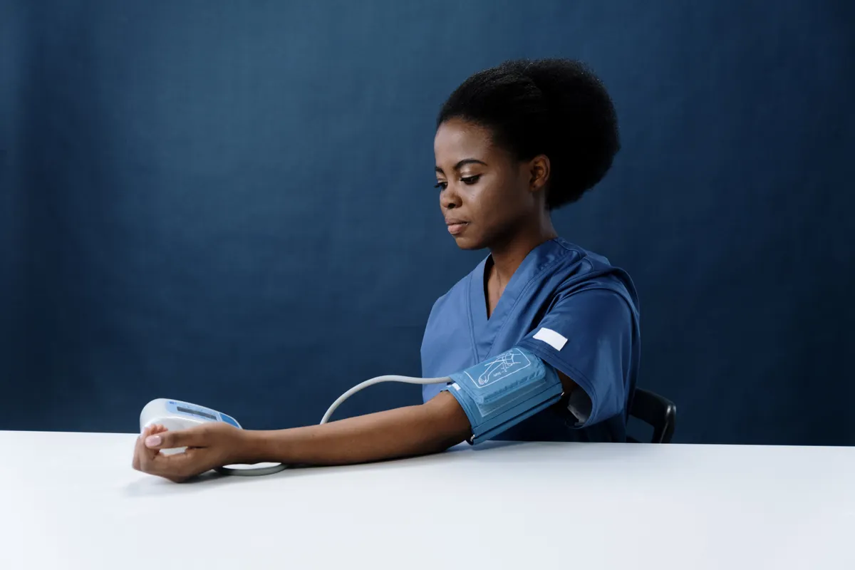 A clinician in scrubs taking a blood-pressure reading.