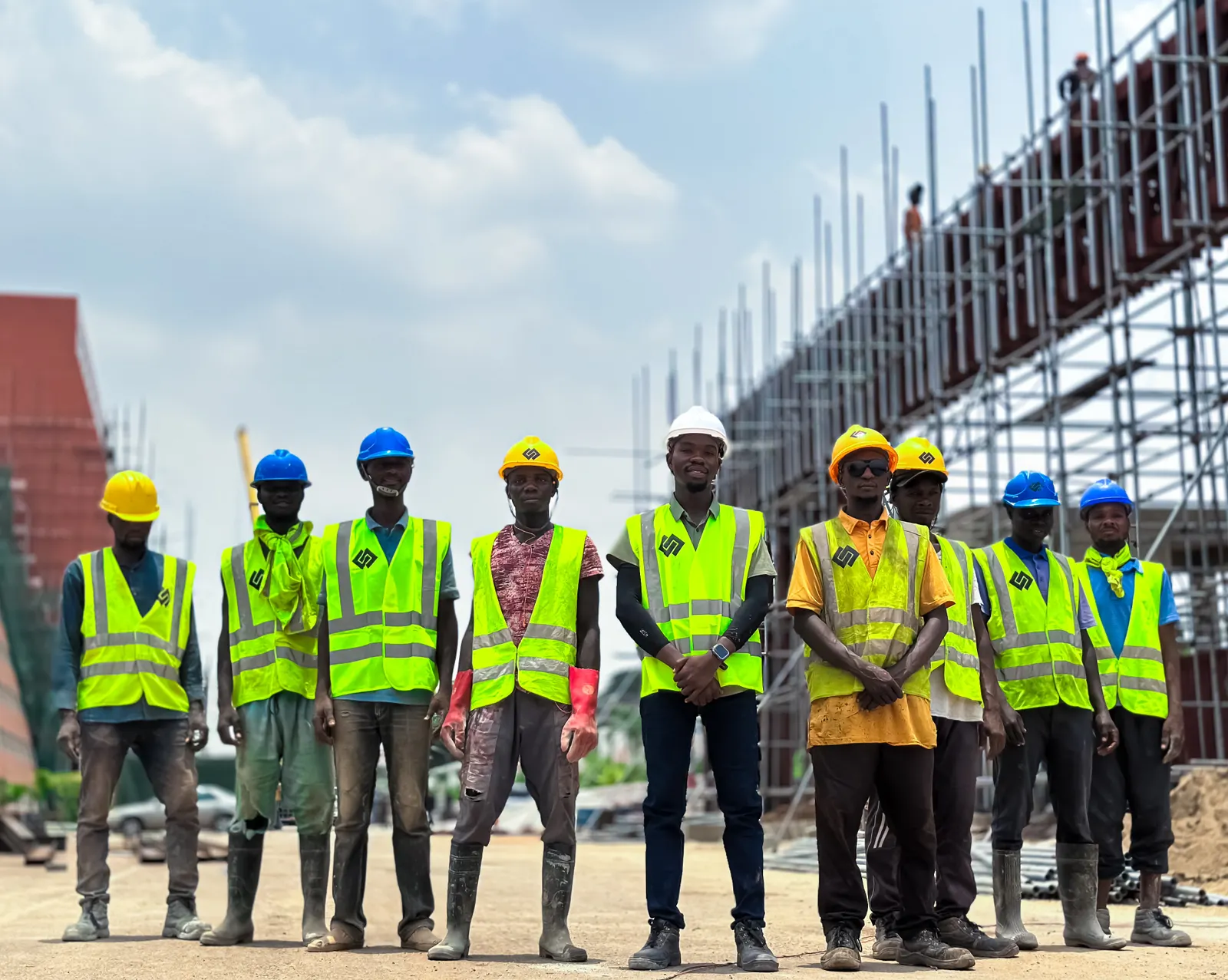 A line of workers in high-visibility vests and hard hats on a site.