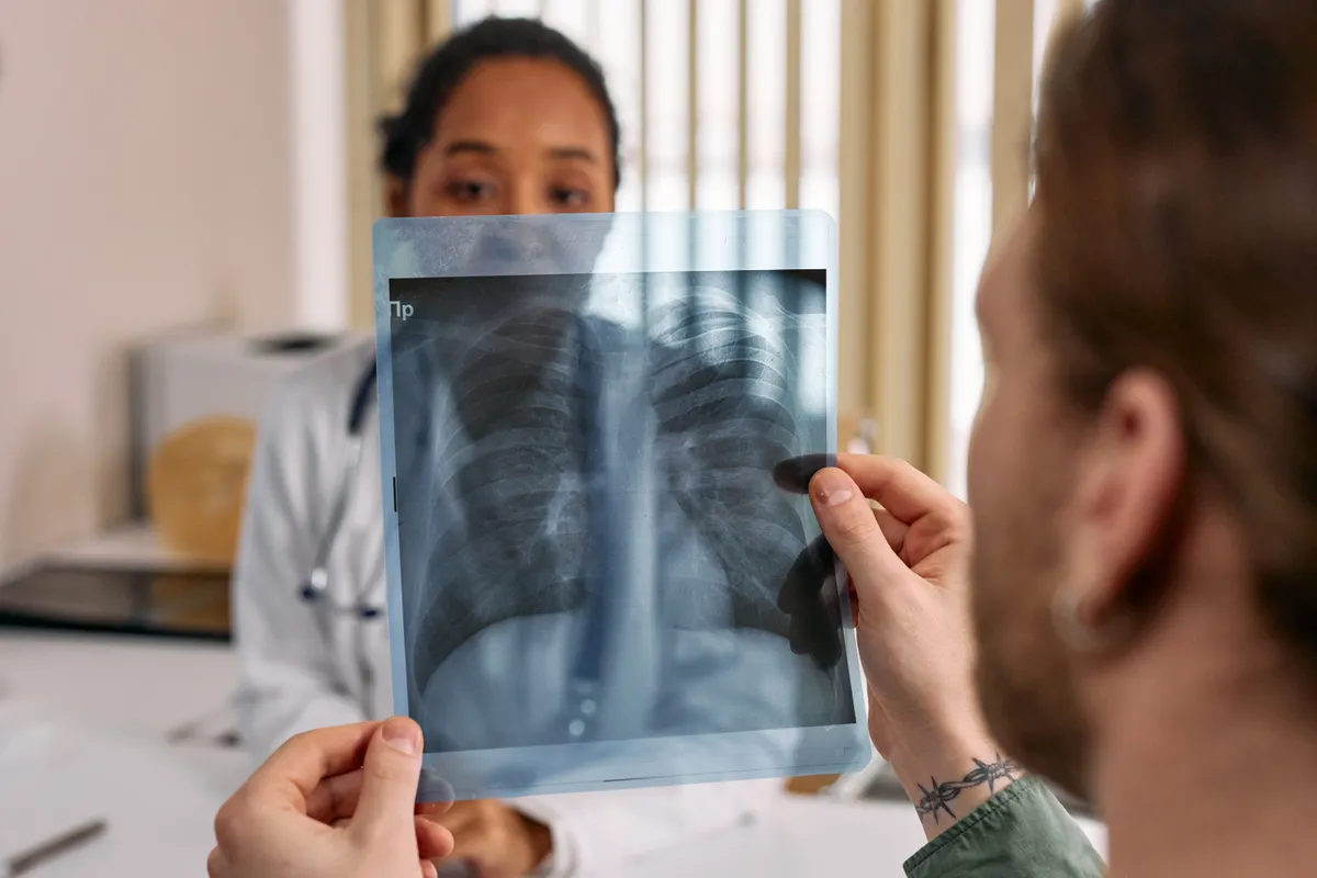 A clinician and a patient looking together at a chest x-ray film.